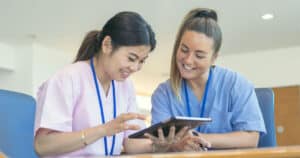 Smiling young nurses using computer tablet together